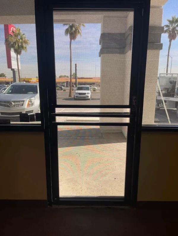 Commercial Storefront Security Screens for Doors and Windows — interior view of a single mesh push door with transom looking out to a Las Vegas parking lot, by Olson Iron