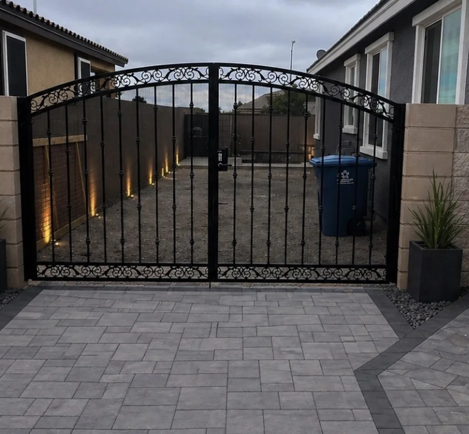 Olson Iron custom RV / driveway gate in Las Vegas — black double-swing rv gate with vertical pickets between stucco pillars at dusk in Las Vegas (710G)
