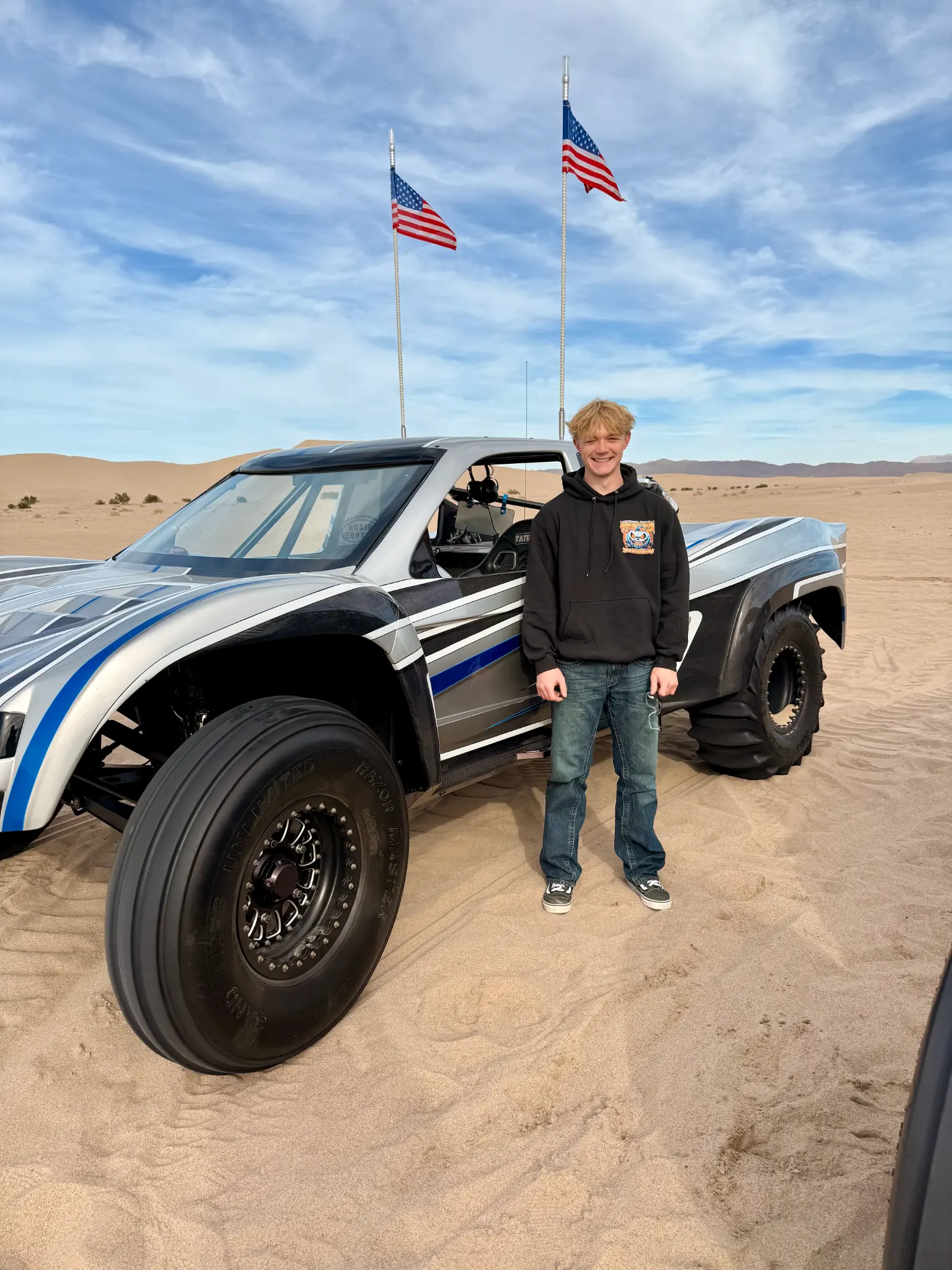 Crew member at the dunes next to a sand vehicle