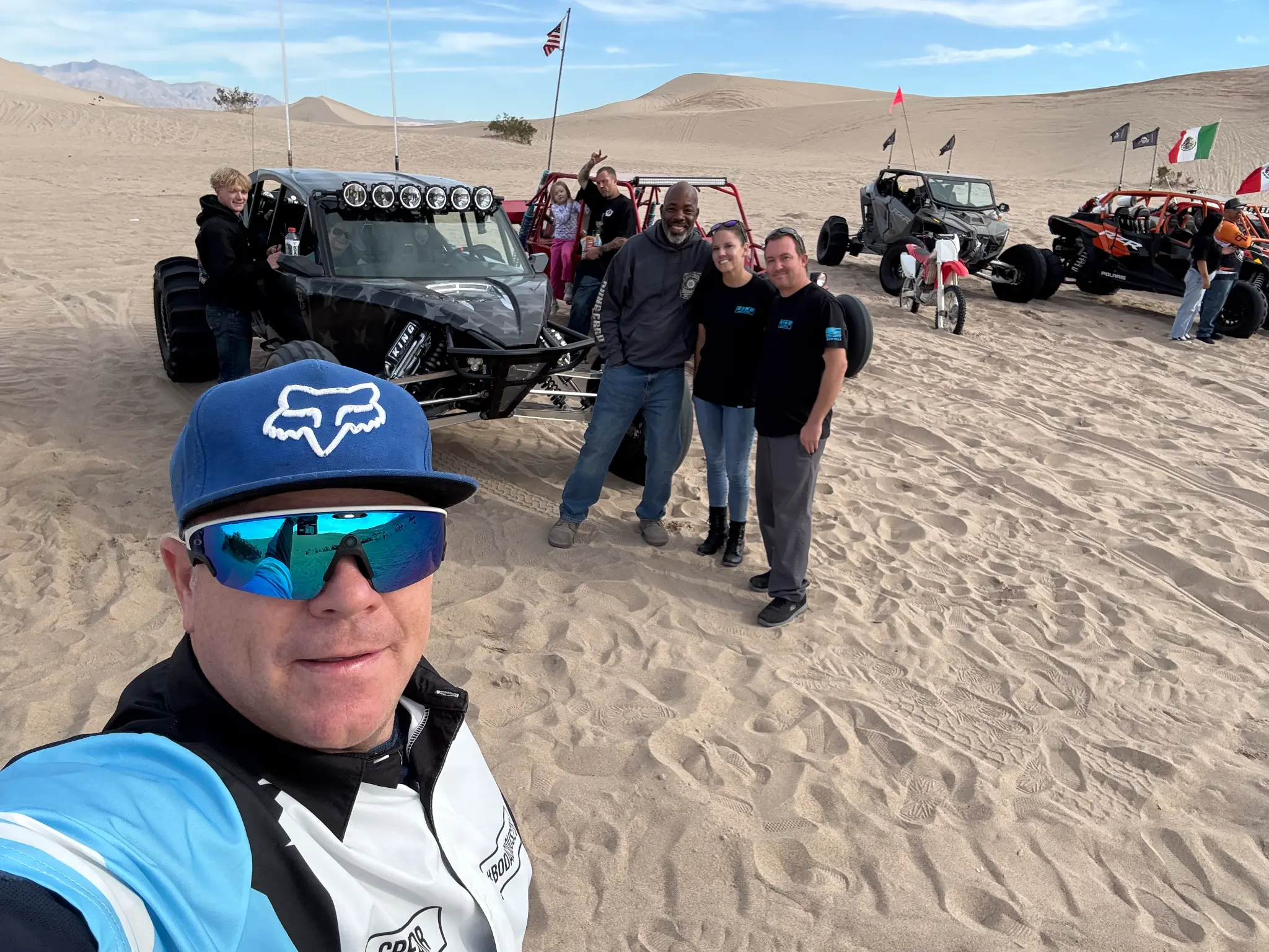 Group of Olson Iron crew at the dunes with off-road vehicles
