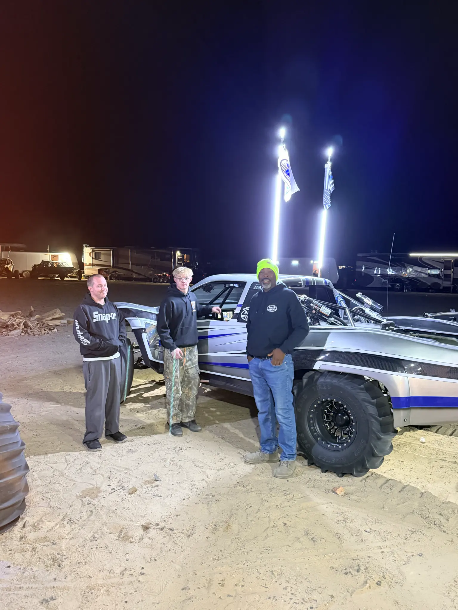 Three Olson Iron crew members at night next to the sand rail
