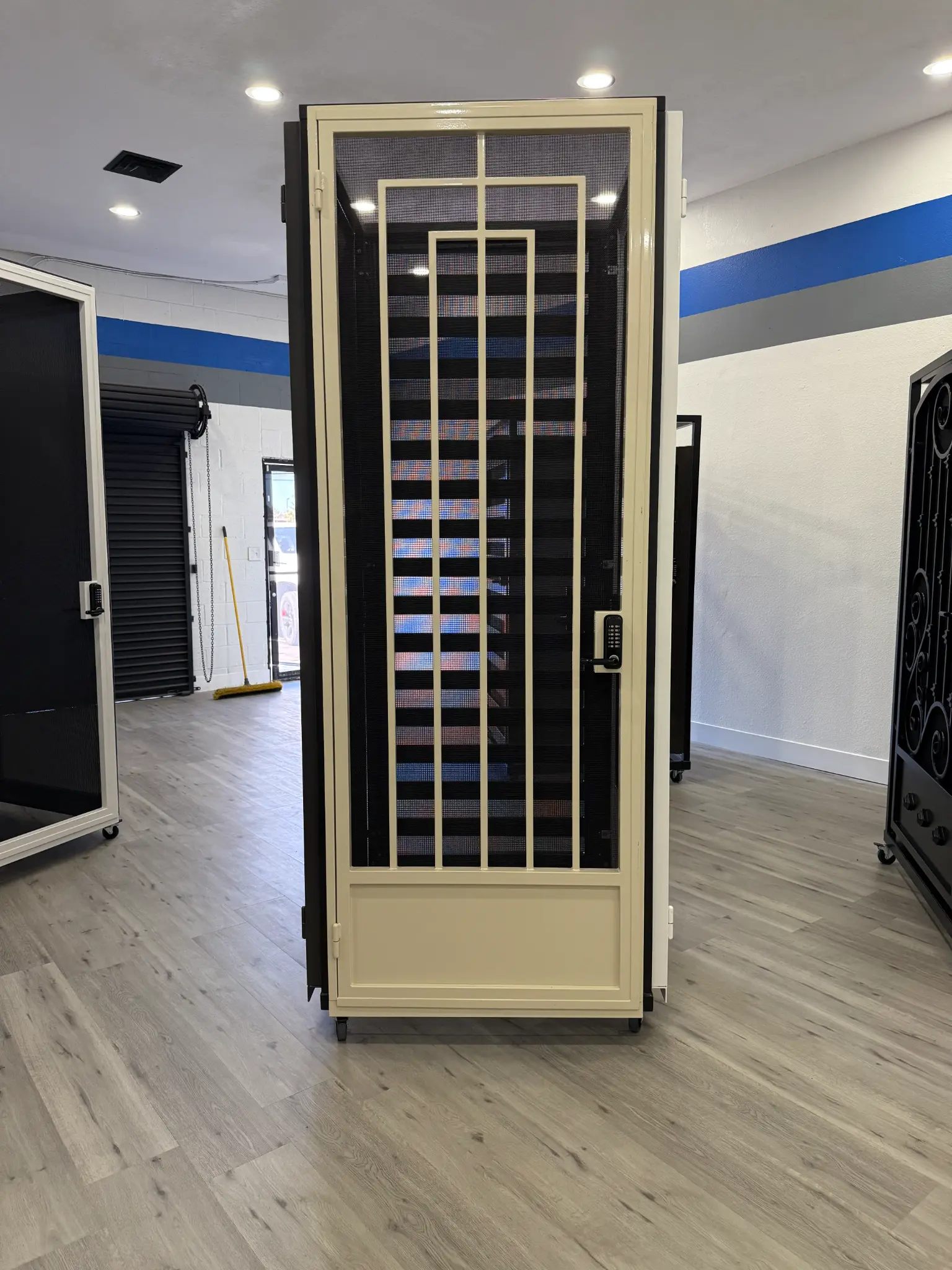 Cream-colored security door with geometric design on display in Olson Iron showroom
