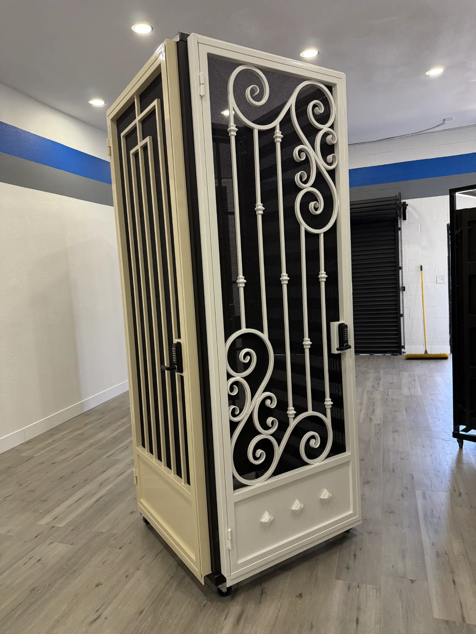 Cream-colored security door with wrought iron scrollwork in Olson Iron showroom