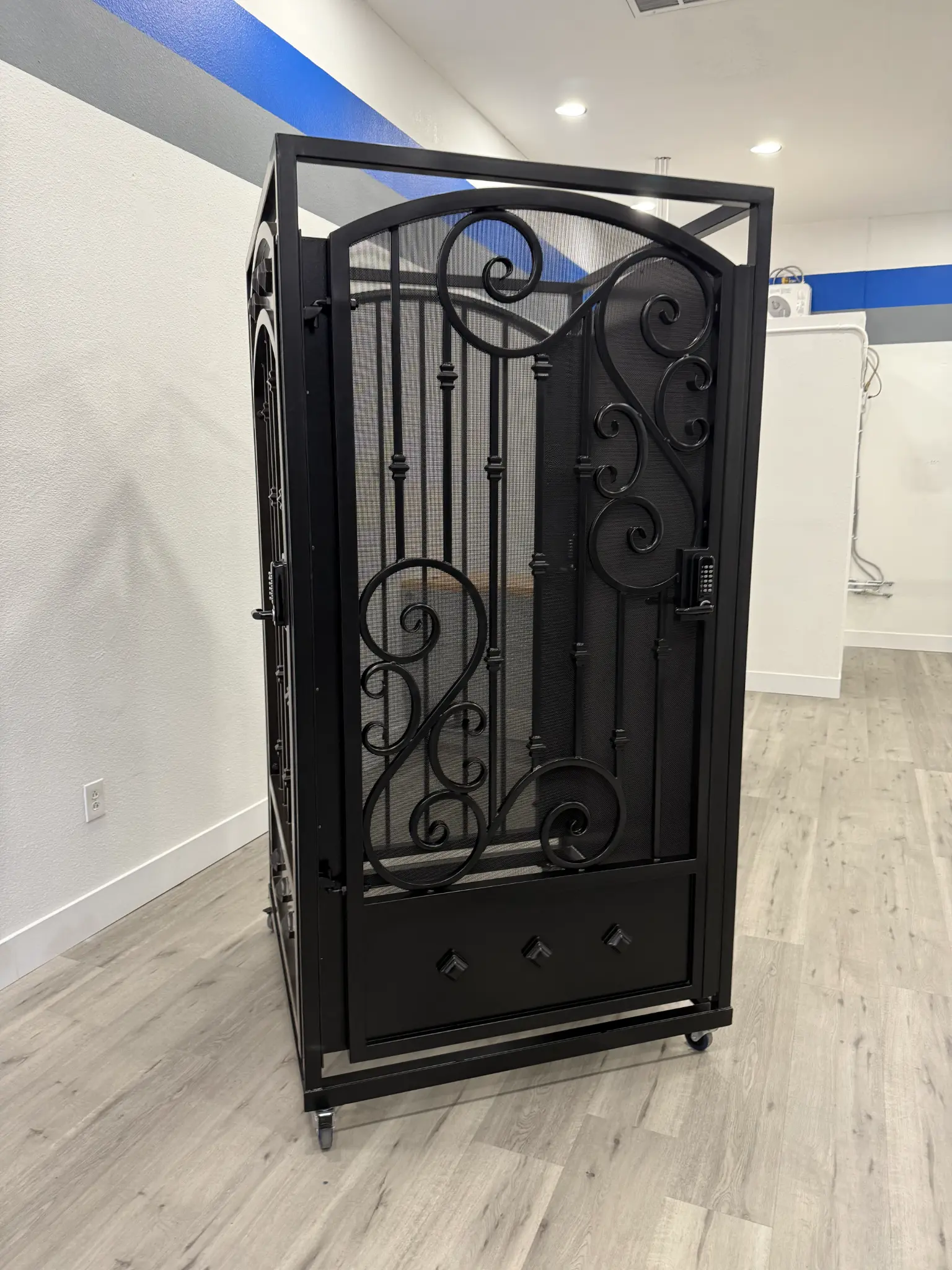 Black ornate metal gate with scrollwork and mesh backing in Olson Iron showroom