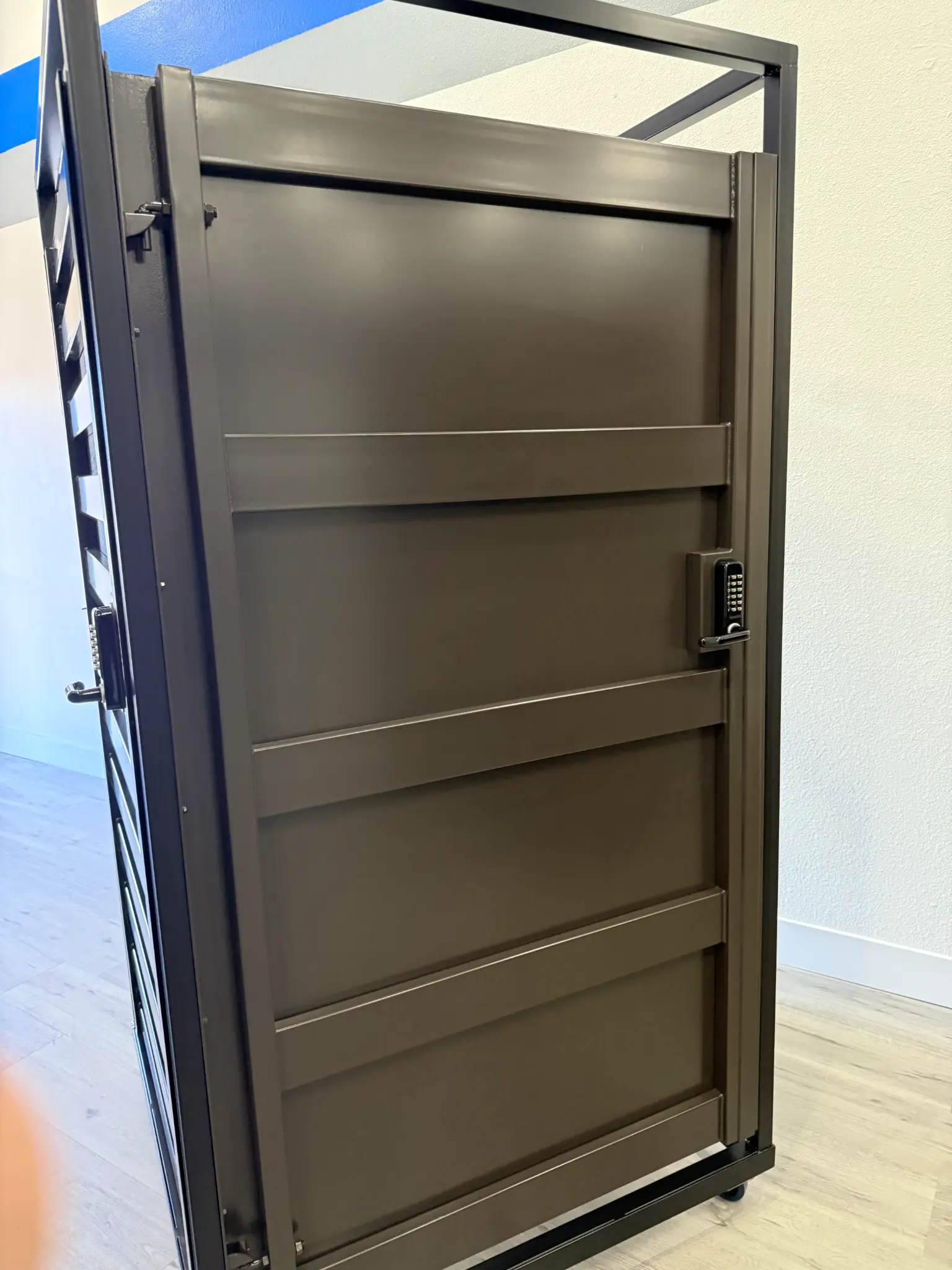 Dark brown slatted metal gate with keypad lock in Olson Iron showroom