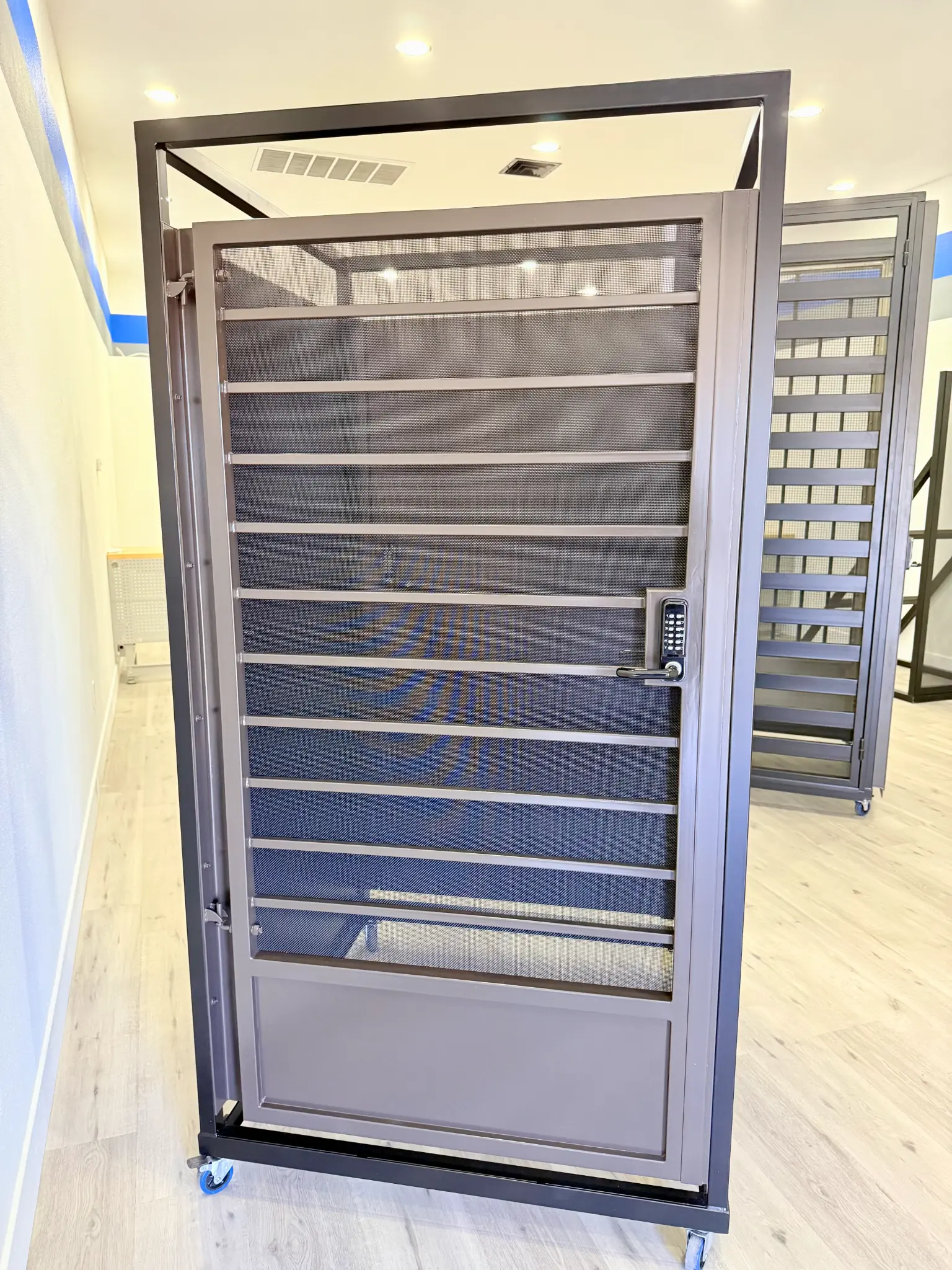 Modern dark gray security screen door with keypad in Olson Iron showroom