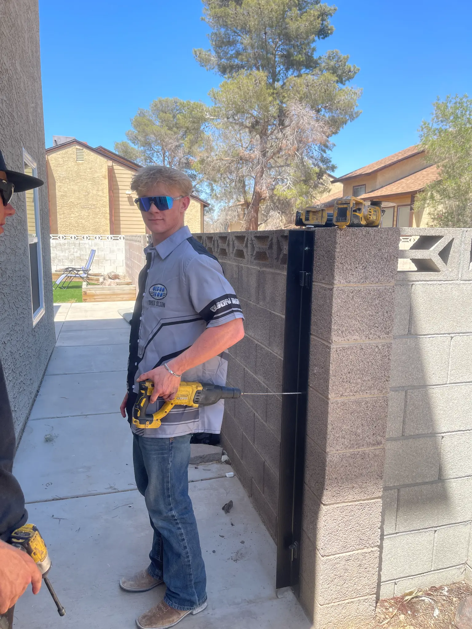 Shea drilling a gate post wearing Olson Iron gear